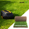 Automatischer Rasenmäher auf einem frisch gemähten Rasen neben einem Stück Rollrasen mit dem Logo "Rollrasen Breuer" und der Aufschrift "LANDSCHAFTSRASEN"